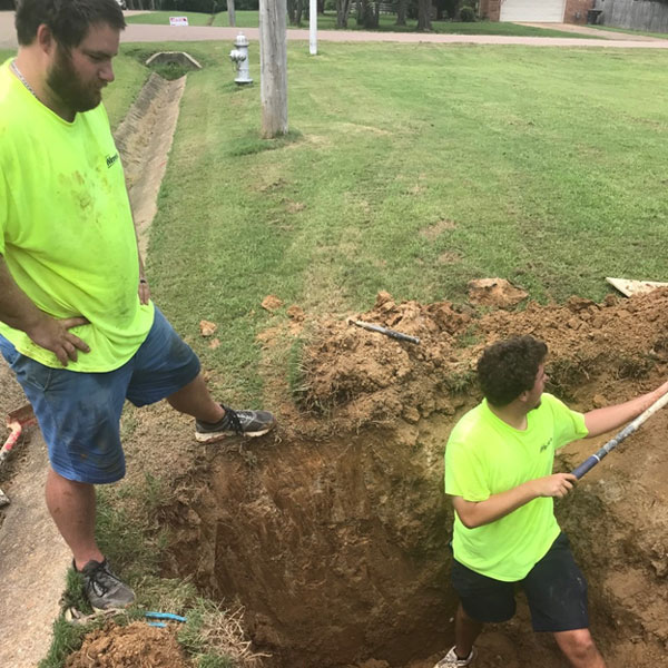 Hugo Plumbing employees digging hole